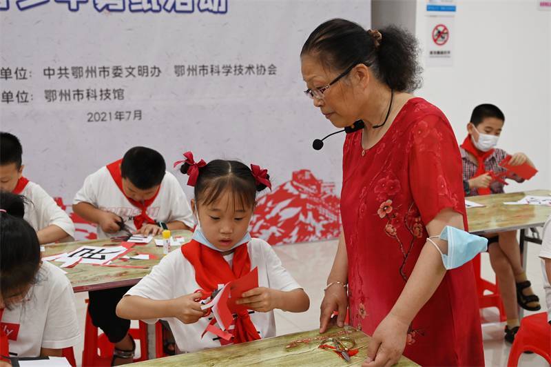 2021年7月10日，鄂州市科協(xié)組織落駕坪小學(xué)學(xué)生在鄂州市科技館開展社會主義核心價值觀系列活動，圖為開展的紅色剪影圓夢中華剪紙活動，老師指導(dǎo)同學(xué)剪紙.jpg